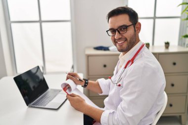 Klinikte çalışan doktor üniforması giyen genç İspanyol adam.