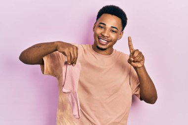 Genç Afro-Amerikalı bir adam elinde çoraplarla gülümsüyor bir fikirle ya da soru işareti yaparak mutlu bir yüzle, bir numara 