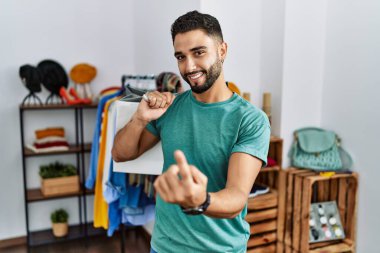 Satış mağazasında sakallı, alışveriş torbası tutan genç yakışıklı adam seni çağırıyor. 