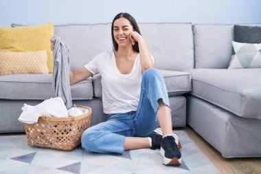 Genç esmer kadın evde çamaşır yıkıyor, kameraya seksi bir ifadeyle bakıyor, neşeli ve mutlu bir yüzle.. 