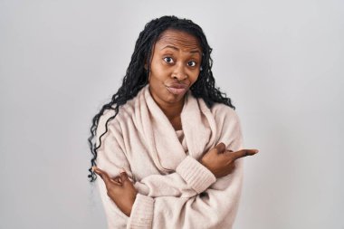 Beyaz arka planda duran Afrikalı kadın her iki tarafı da parmaklarıyla işaret ediyor. Farklı yönler farklı. 