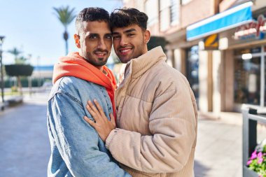 İki erkek caddede birbirlerine sarılıyorlar.