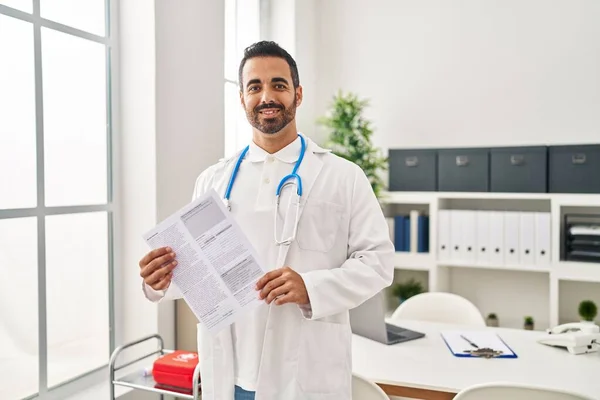 Young Hispanic Man Wearing Doctor Uniform Holding Report Document Clinic — 图库照片