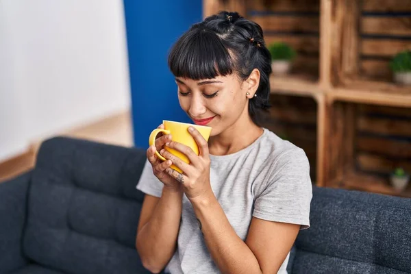 Νεαρή Γυναίκα Πίνει Καφέ Καθισμένη Στον Καναπέ Στο Σπίτι — Φωτογραφία Αρχείου