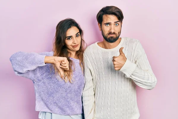 Young Hispanic Couple Wearing Casual Clothes Doing Thumbs Disagreement Agreement — Stockfoto