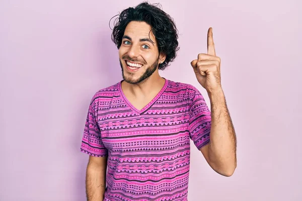 カジュアルなピンクのTシャツを着たハンサムなヒスパニック系の男性が成功したアイデアで指を指しています 興奮して幸せよ 第1位 — ストック写真