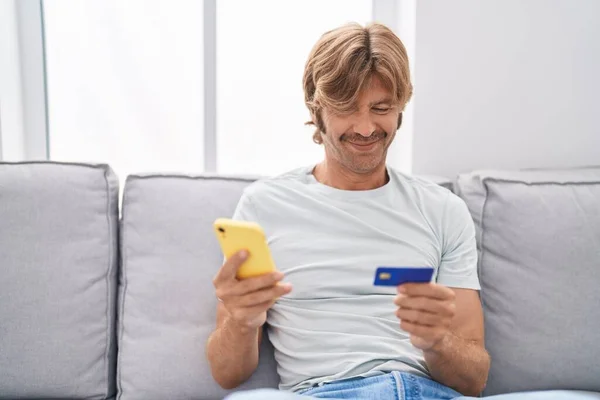 Junger Mann Sitzt Mit Smartphone Und Kreditkarte Hause Auf Sofa — Stockfoto