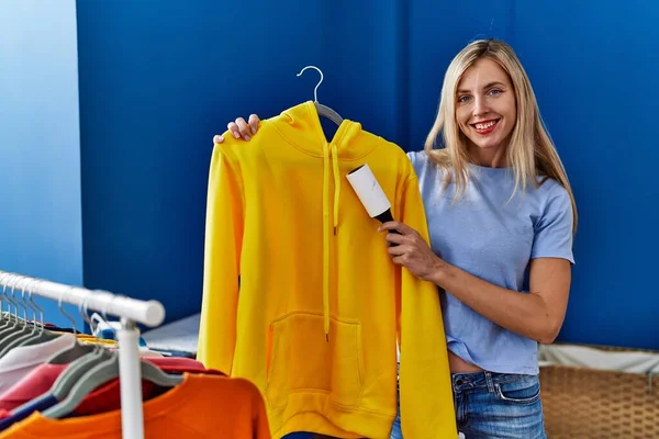 Young Blonde Woman Smiling Confident Cleaning Clothes Using Hair Pet — Zdjęcie stockowe