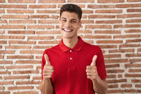 Young Hispanic Man Standing Bricks Wall Success Sign Doing Positive —  Fotos de Stock