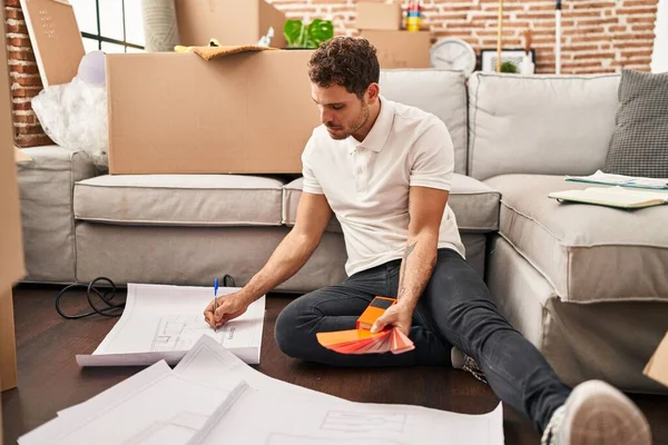 Young Hispanic Man Writing Plans Sitting Floor New Home — Stockfoto