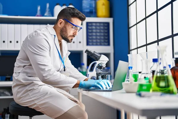 Young Hispanic Man Wearing Scientist Uniform Using Laptop Microscope Laboratory — Stockfoto