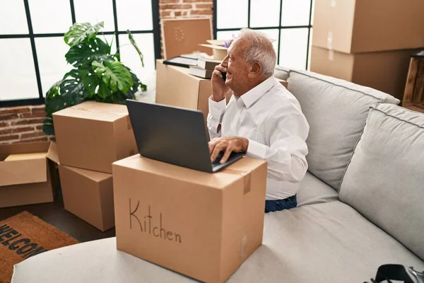 Hombre Mayor Usando Ordenador Portátil Hablando Teléfono Inteligente Nuevo Hogar — Foto de Stock