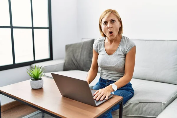 Middle Age Blonde Woman Using Laptop Home Shock Face Looking — Foto de Stock