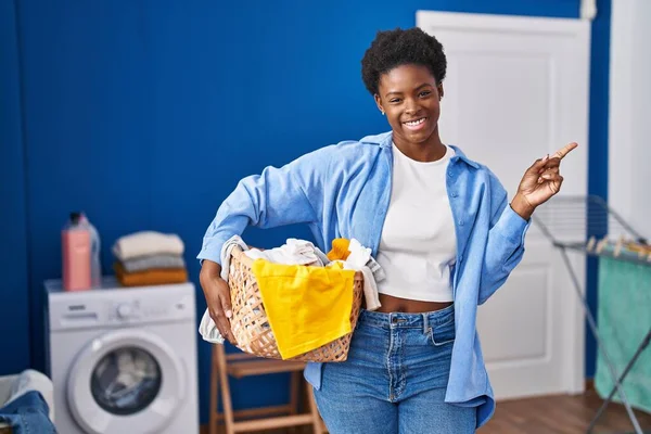 African American Woman Holding Laundry Basket Smiling Happy Pointing Hand — Fotografia de Stock