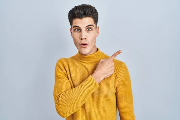 Young Hispanic Man Standing Blue Background Surprised Pointing Finger Side — Stock Photo, Image
