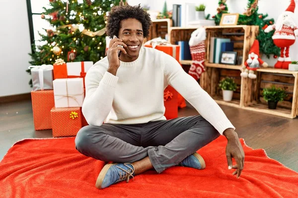 Молодой Африканский Американец Разговаривает Смартфону Сидя Полу Рождественской Елки Дома — стоковое фото