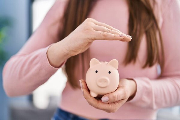 Young woman holding piggy bank at home