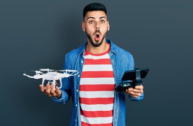 Sakallı, uzaktan kumandalı İHA kullanan genç İspanyol adam şaşkınlık ve şaşkınlık dolu bir ifade, korku ve heyecanlı bir yüz ifadesiyle dehşete düştü.. 