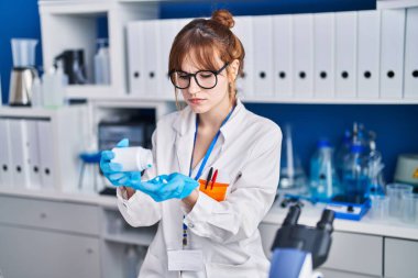 Laboratuvarda elinde haplar tutan genç bir bilim kadını.