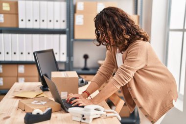 Orta yaşlı İspanyol kadın ecommerce 'de dizüstü bilgisayarla çalışıyor.