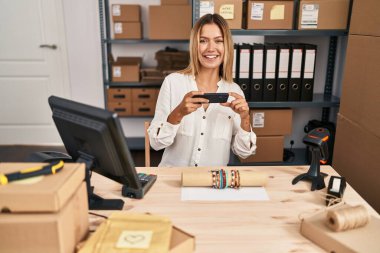 Genç İspanyol kadın ecommerce işçisi ofiste bilezik fotoğrafına bakıyor.