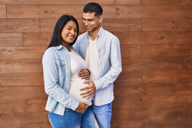 Genç Latin çift sokakta karnına dokunacak bir bebek bekliyor.