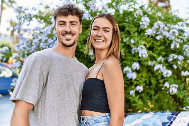 Genç İspanyol çift mutlu bir şekilde gülümsüyor ve şehirde birbirlerine sarılıyorlar..