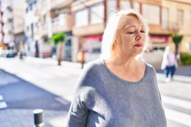 Sokakta duran orta yaşlı sarışın kadın.