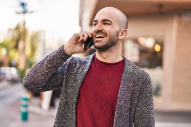 Genç adam gülümsüyor. Kendine güveniyor. Sokakta akıllı telefondan konuşuyor.