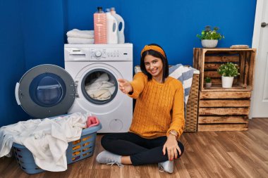 Genç İspanyol kadın çamaşır yıkıyor. Dostça gülümsüyor. Karşılama ve hoş geldin demek için tokalaşıyor. başarılı iş. 