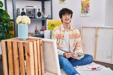 Genç İspanyol ressam, resim stüdyosunda kendine güvenen gülümsüyor.