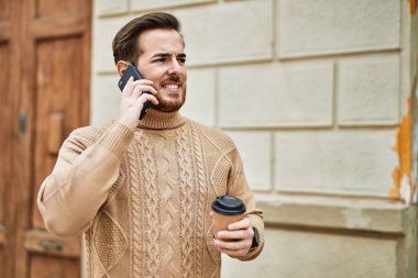 Kafkasyalı genç adam akıllı telefondan konuşuyor. Şehirde kahve içiyor..