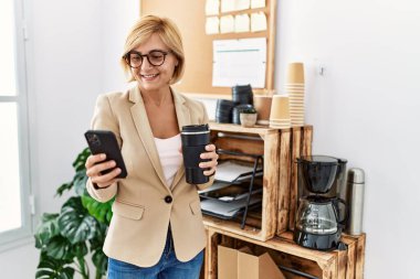 Ofiste kahve içen orta yaşlı sarışın kadın.