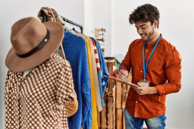 Genç İspanyol esnaf gülümsüyor. Giyim mağazasında çalışan panoya mutlu yazılar yazıyor..