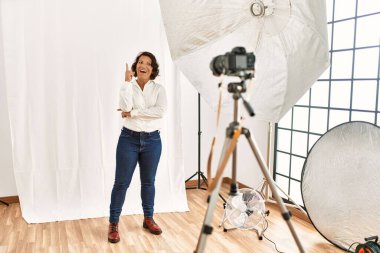 Fotoğrafçılık stüdyosunda model kılığına girmiş orta yaşlı İspanyol bir kadın başarılı bir fikirle işaret ediyor. Heyecanlı ve mutlu. Bir numara.. 