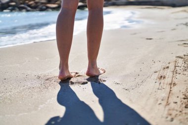 Genç İspanyol kadın deniz kenarında kumda yürüyor.