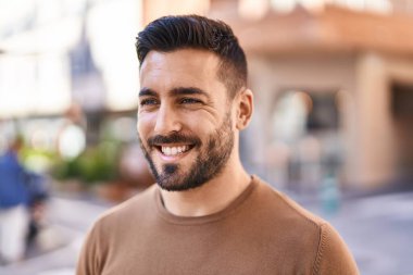 Sokakta kendinden emin gülümseyen İspanyol genç adam.