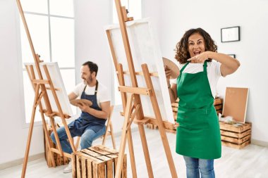 İspanyol orta yaşlı kadın ve sanat stüdyosunda olgun bir adam mutlu bir şekilde el ve parmak işareti yapıyor. 