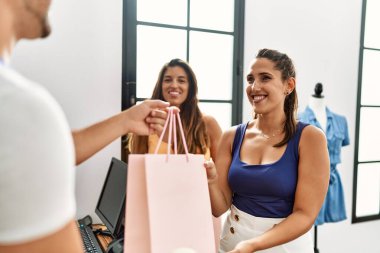 Genç İspanyol esnaf elbise dükkanındaki müşteriye alışveriş çantası veriyor..