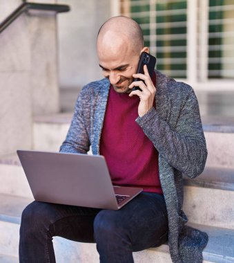 Sokakta dizüstü bilgisayarla konuşan genç bir adam.