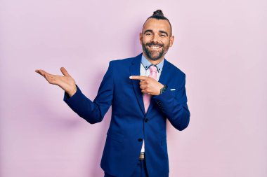 Genç İspanyol adam iş elbisesi giyiyor ve kravat takıyor kameraya hayret ediyor ve gülümsüyor.. 