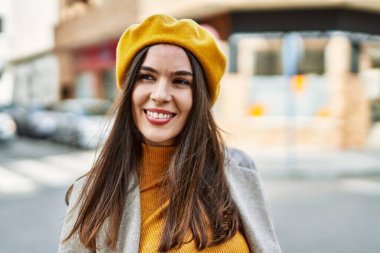 Genç İspanyol kız gülümseyerek şehirde mutlu mesut dikiliyor..