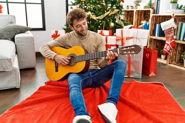 Jovem Hispânico Tocando Guitarra Sentada Árvore Natal Casa — Fotografia de Stock