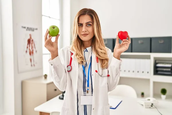 Νεαρή Ξανθιά Γιατρός Γυναίκα Κρατώντας Την Καρδιά Και Πράσινο Μήλο — Φωτογραφία Αρχείου