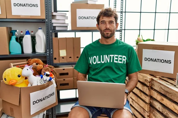 Young Handsome Man Wearing Volunteer Shirt Using Laptop Relaxed Serious — Stock Photo, Image