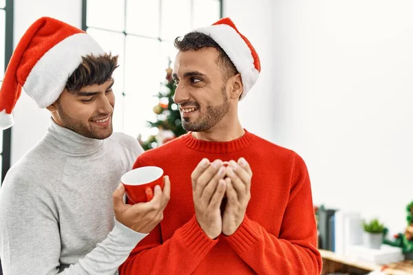 Two Hispanic Men Couple Drinking Coffee Standing Christmas Tree Home — Stock Photo, Image