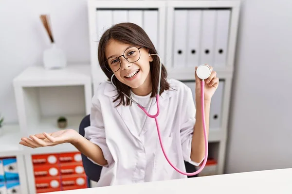 Young Hispanic Girl Wearing Doctor Coat Holding Stethoscope Celebrating Achievement — Stok fotoğraf