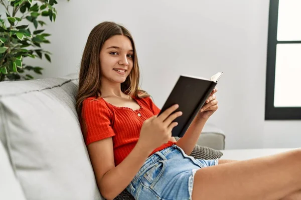 Urocza Dziewczyna Uśmiecha Się Pewnie Czytając Książkę Domu — Zdjęcie stockowe