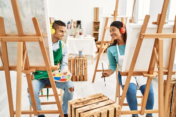 年轻的拉丁画家夫妇笑容满面 在艺术工作室使用耳机 — 图库照片