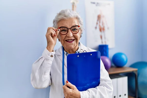 Senior Mulher Cabelos Grisalhos Vestindo Fisioterapeuta Uniforme Segurando Checklist Clínica — Fotografia de Stock